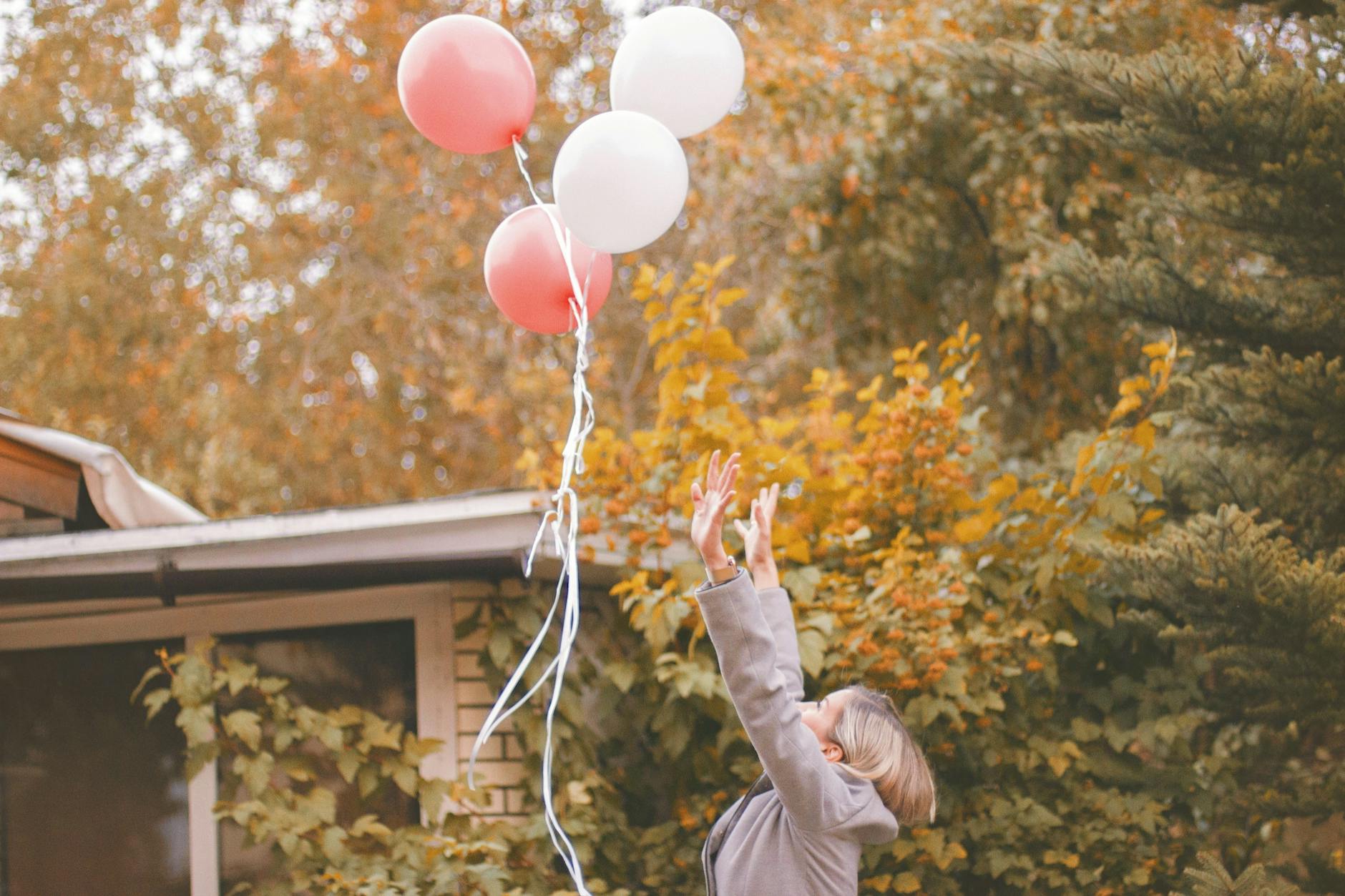 woman in gray jacket released balloons in the air